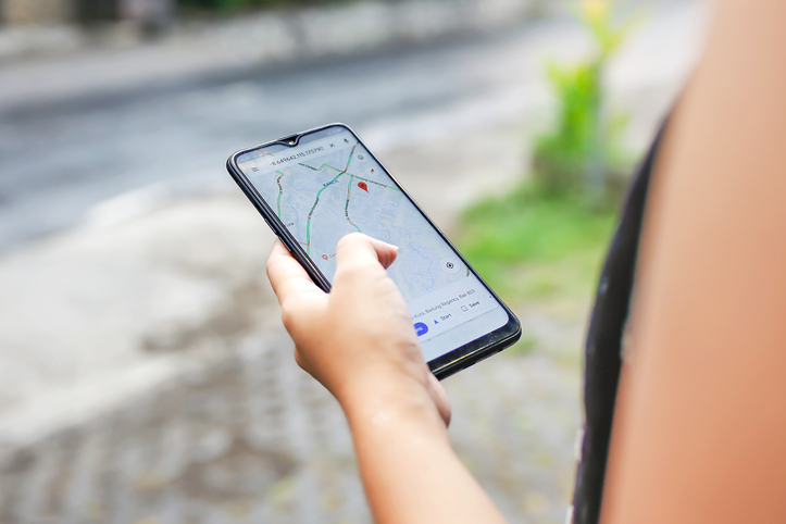 Person hält ein Smartphone in der Hand, auf dem eine Karten- oder Navigations-App geöffnet ist