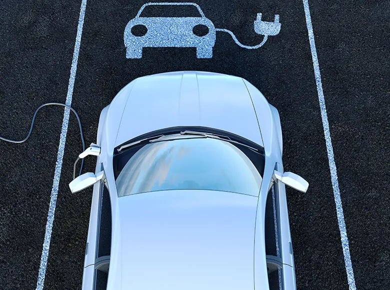 Elektroauto lädt an Ladestation auf Parkplatz
