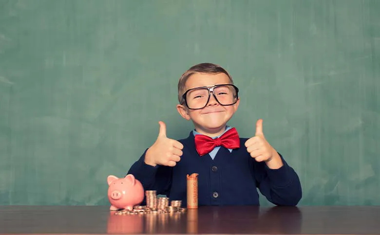 Kind mit Brille und Sparschwein zeigt Daumen hoch