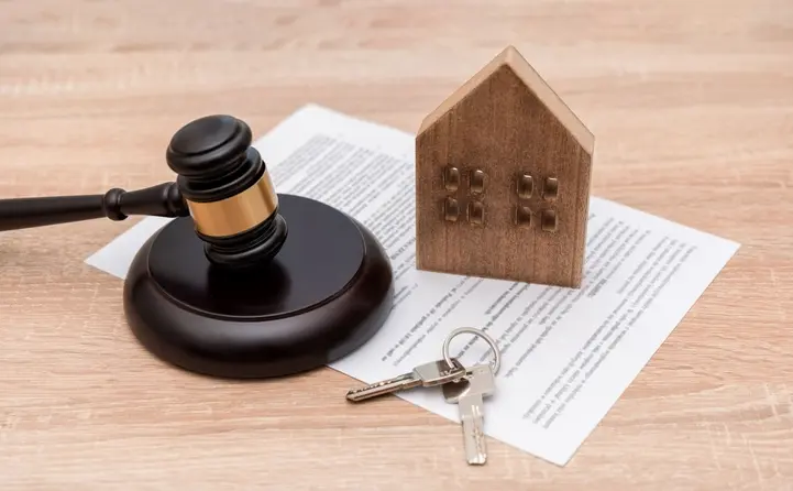 Symbolbild für Mietrecht: Ein kleines Spielzeughaus und ein Justiziarhammer auf einem Mietvertrag.