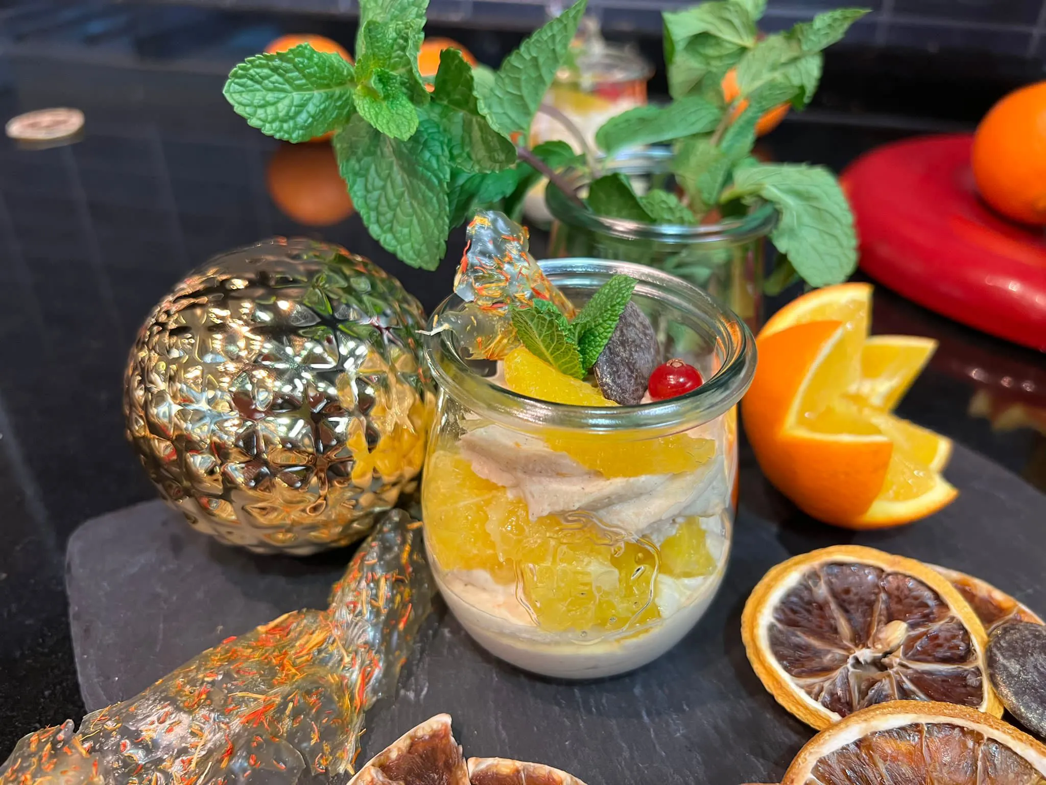 Lebkuchencreme in einem Glas serviert, dekoriert mit frischer Minze, Orangenscheiben und roten Beeren. 