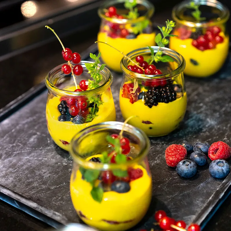 Mangocreme im Glas, dekoriert mit frischen Beeren und Minze.