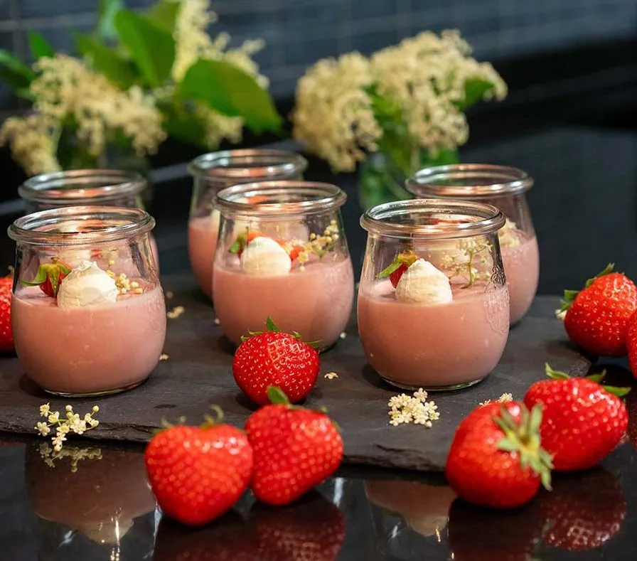 Erdbeer-Panna-Cotta im Glas, garniert mit frischen Erdbeeren und Sahne.