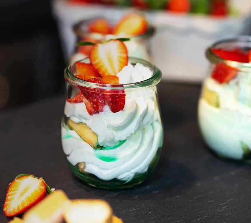 Waldmeister-Tiramisu im Glas, dekoriert mit frischen Erdbeerscheiben.