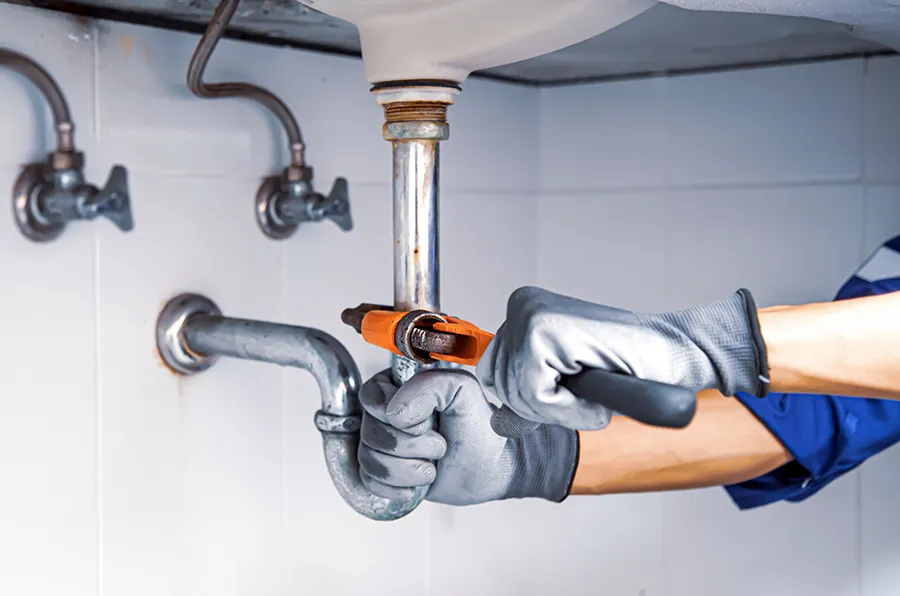 Handwerker repariert Rohr unter einem Waschbecken.