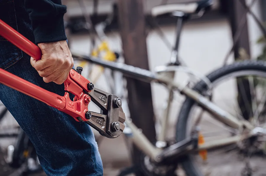 Person mit Bolzenschneider vor einem Fahrrad.