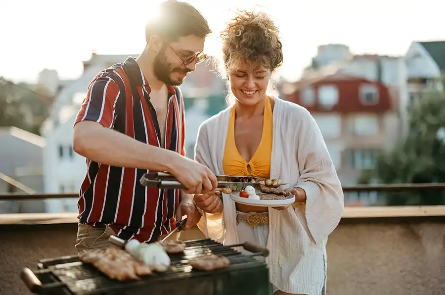 Paar grillt auf ihrem Balkon.