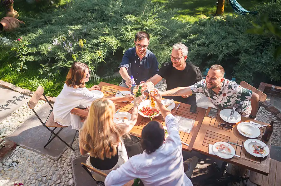 Eine Gruppe sitzt um einen Tisch im Garten und stößt an.