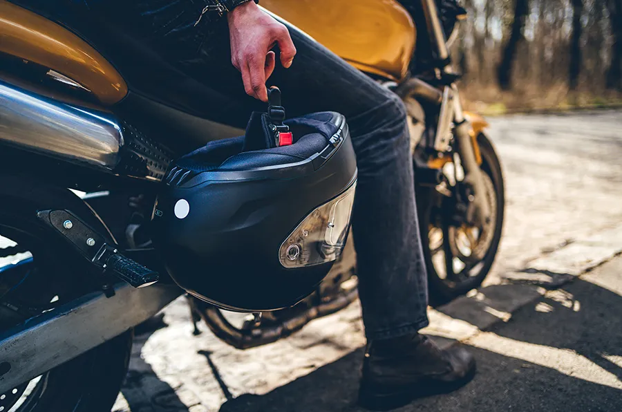 Person hält Motorradhelm in der Hand.