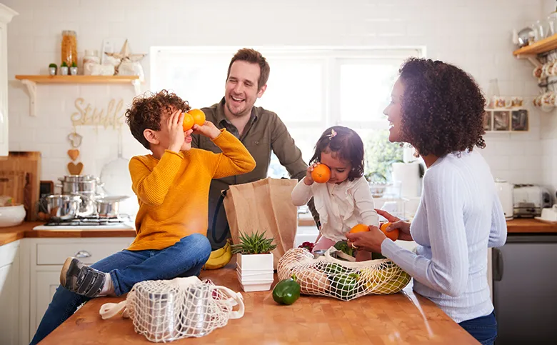 Eine Familie steht in einer Küche und packt Einkäufe in wiederverwendbare Netztaschen aus.