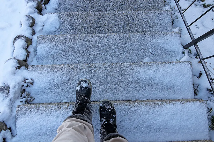 Füße in Schneeschuhen auf einer zugefrorenen Treppe. 