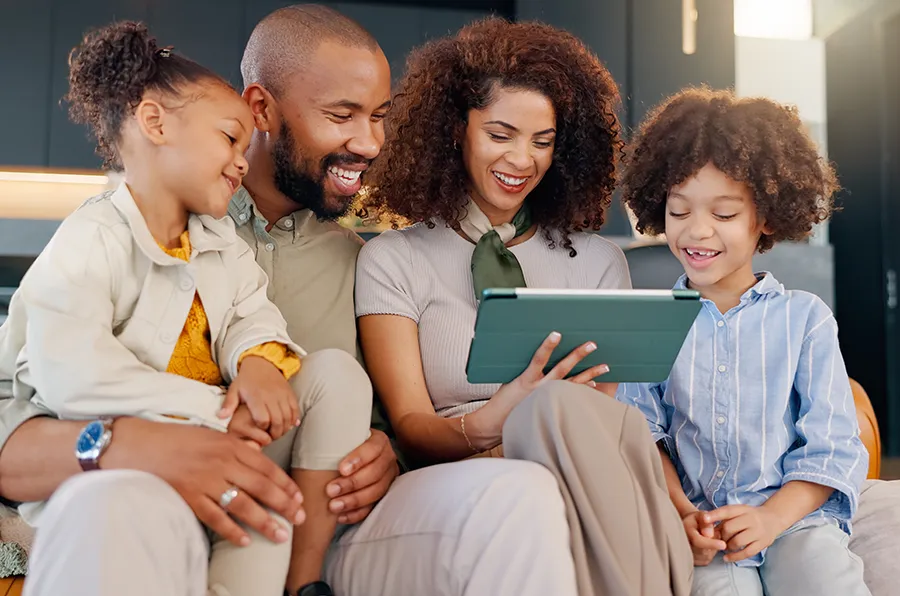 Eine Familie sitzt zusammen und schaut in ein Tablet.