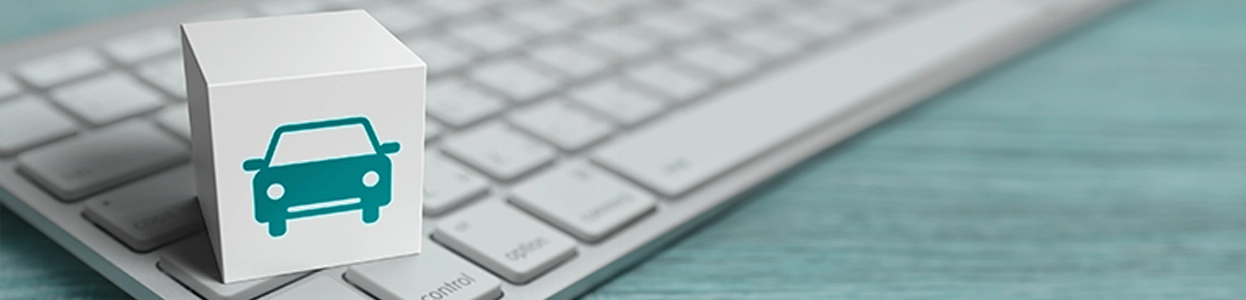 Würfel mit Autosymbol steht auf einer Computertastatur, Symbolbild für digitale Kfz-Versicherung oder Online-Autoanmeldung
