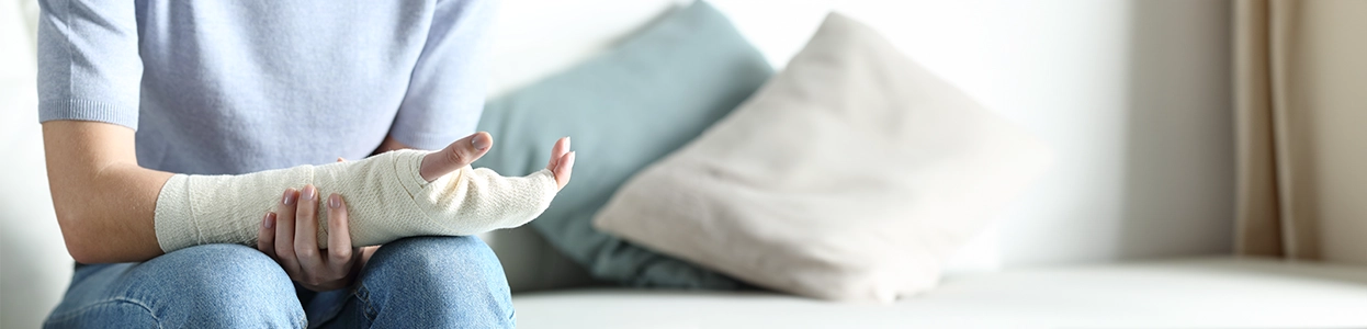 Person sitzt auf einem Sofa und hält ihren bandagierten Arm