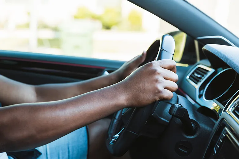 Nahaufnahme von Händen am Lenkrad eines Autos während der Fahrt