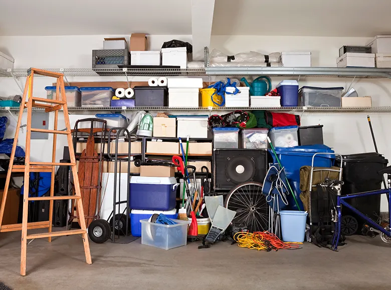 Überfüllte Garage mit Leiter, Kartons, Werkzeugen und verschiedenen Haushaltsgegenständen