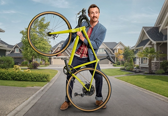 Ein fröhlicher Mann hält stolz sein Fahrrad hoch.