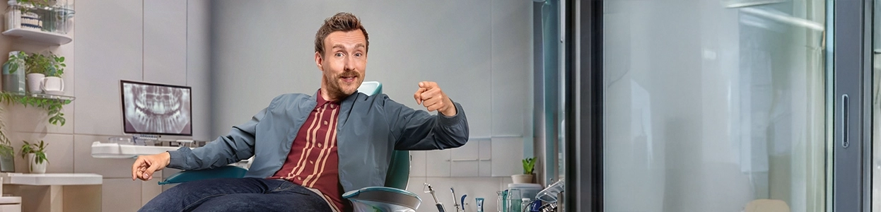 Ein fröhlicher Mann sitzt in einem Zahnarztstuhl.