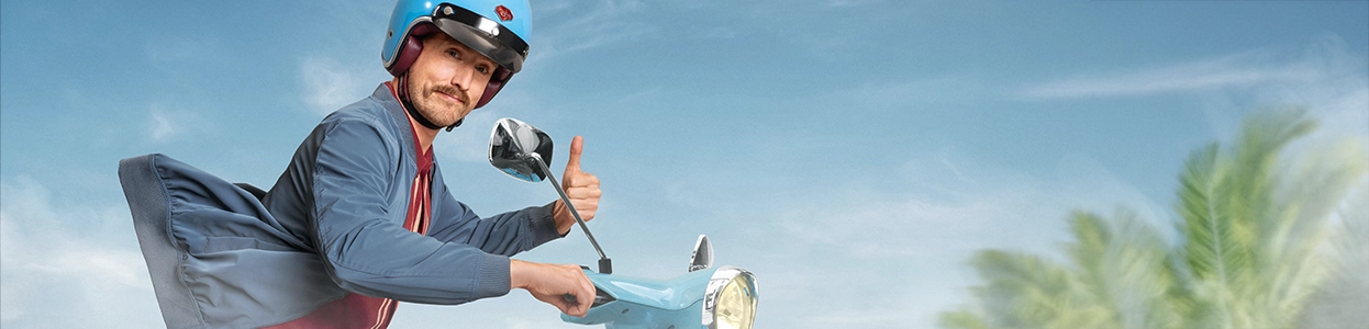 Ein lächelnder Man auf einem Moped auf der Straße.