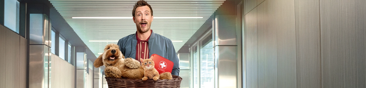 Ein begeistert guckender Mann mit einem Korb gefüllt mit einem Hund, einer Katze und einem erste Hilfe Kasten.
