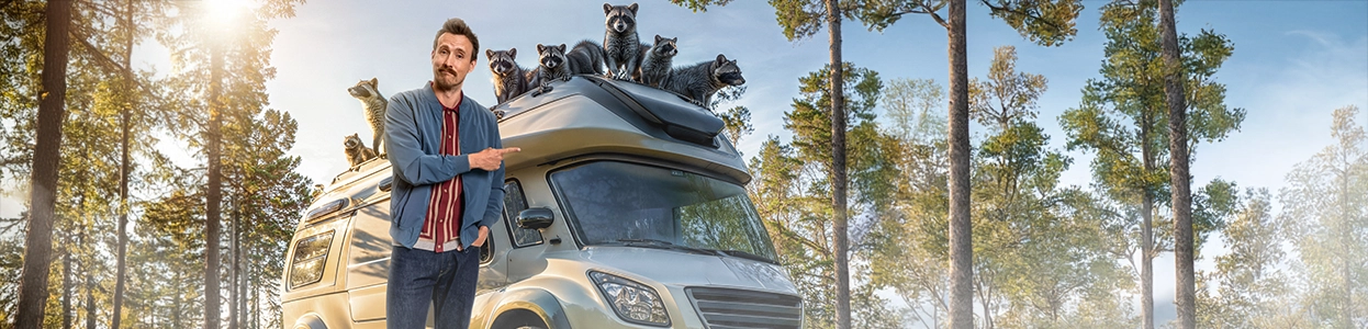 Ein freundlicher Mann steht vor einem Wohnmobil, auf dem eine große Waschbärfamilie sitzt.