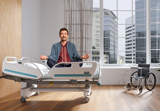Ein Mann sitzt entspannt im Schneidersitz in einem Krankenbett.