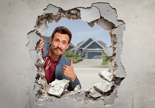 Ein lächelnder Mann schaut durch ein Loch in der Wand.