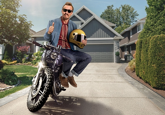 Ein freundlicher Mann sitzt stolz auf seinem Motorrad.